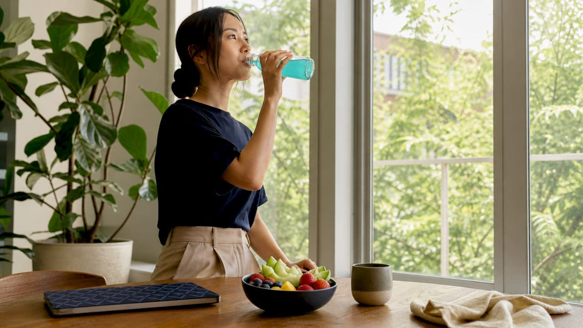 Woman drinking nootropic beverage at kitchen table