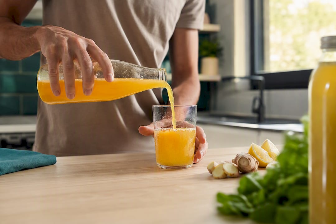Hands pouring vitamin drink into glass